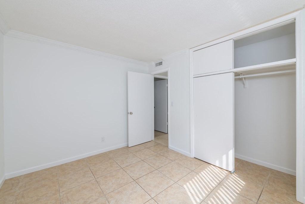 an empty bedroom with a closet and a tiled floor