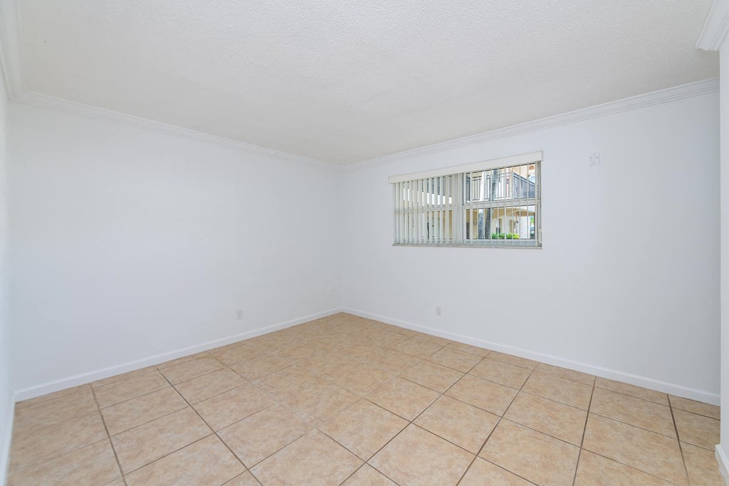 an empty living room with a window and a tiled floor