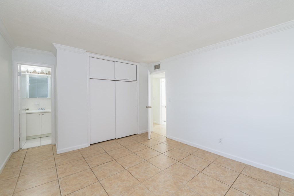 the living room and kitchen of a house with white walls and a tiled floor