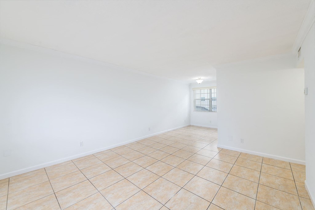 the living room and dining room of a home with white walls and tile flooring