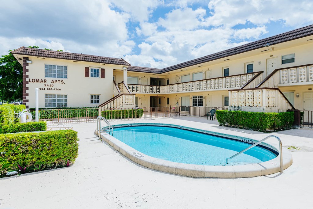 a swimming pool in front of a building with a resort style pool