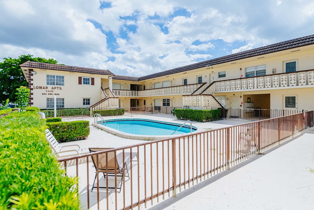 a swimming pool in front of a building with a resort style pool