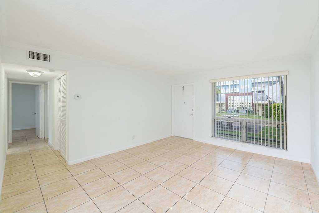 an empty living room with a large window and a tiled floor