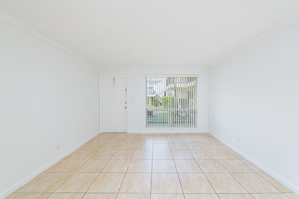 an empty living room with tile flooring and a window