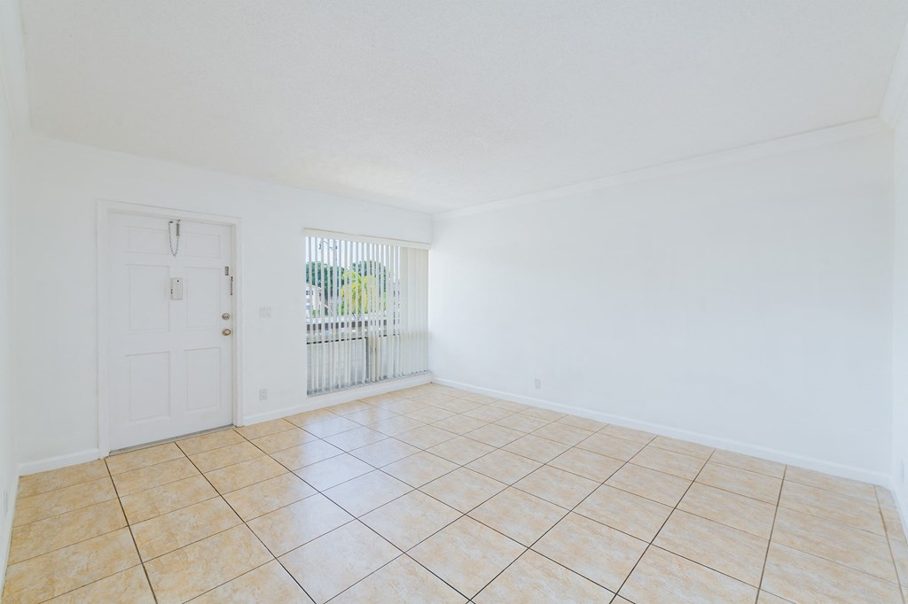 an empty living room with a tile floor and a white door