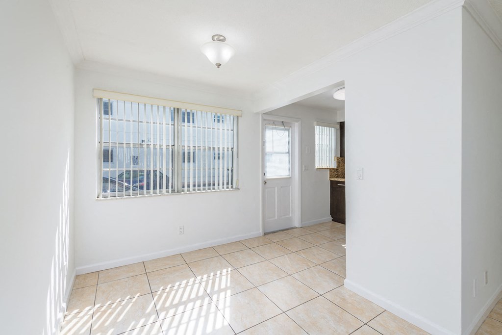 an empty living room with a window and a tiled floor
