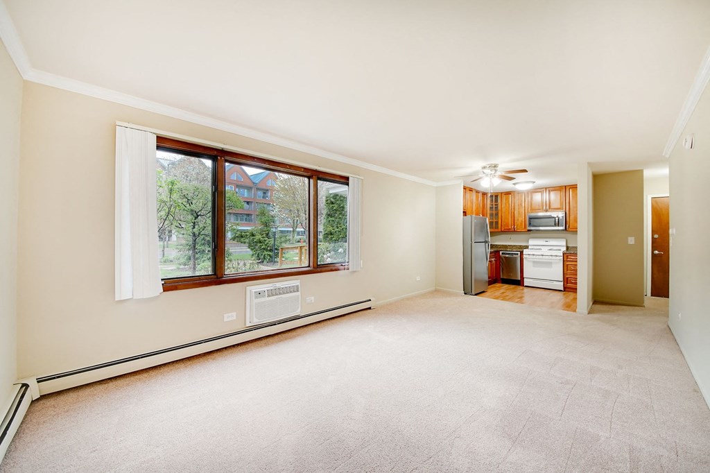 an empty living room with a large window and a kitchen