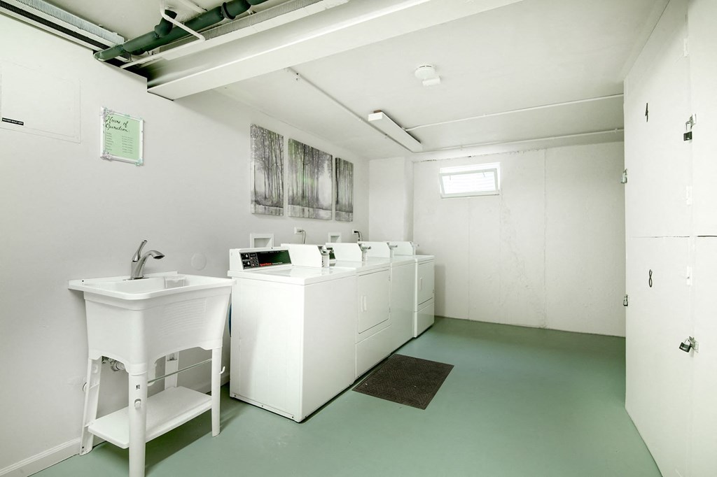 the laundry room has four sinks and a row of washing machines
