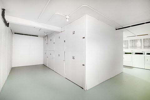 A white room with numbered doors and a white cabinet with a black handle.