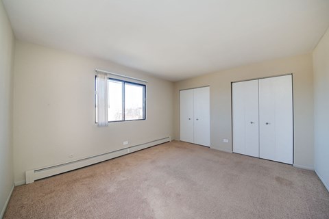 the living room of a home with white walls and a window