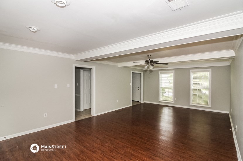 an empty living room with wood floors and a ceiling fan