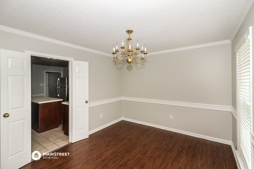 a dining room with a chandelier and a door to the kitchen