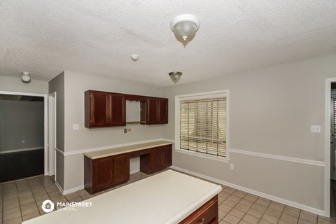 a kitchen with white countertops and wooden cabinets and a window