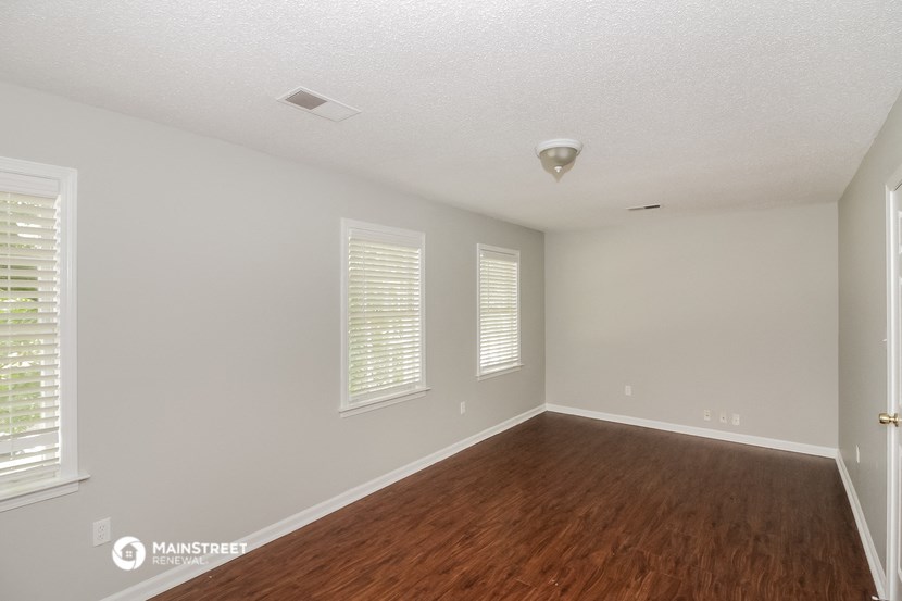 the spacious living room with hardwood flooring and white walls