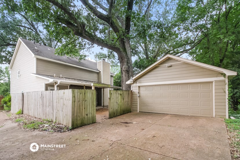 a house and a garage with a driveway and a tree