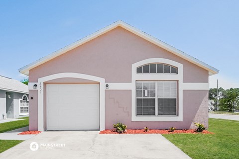a pink house with a garage door and a lawn