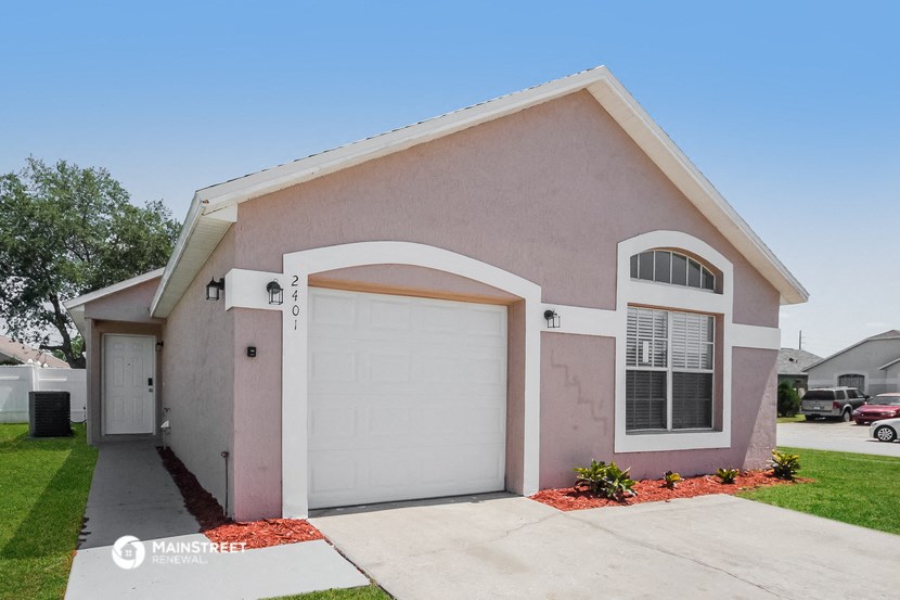 a pink house with a white garage door and a driveway