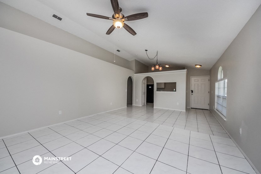 an empty living room with a ceiling fan and a white tiled floor