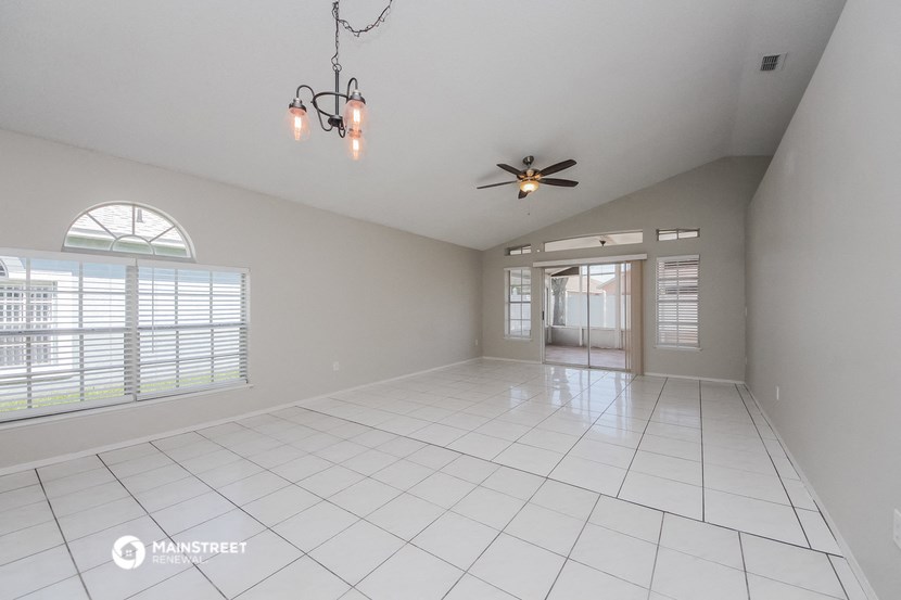 an empty living room with windows and a ceiling fan
