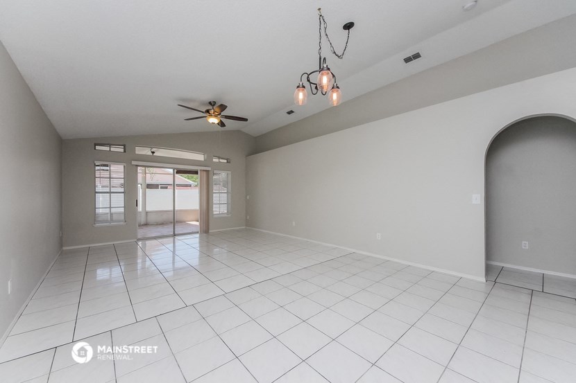 an empty living room with a ceiling fan and a white tile floor