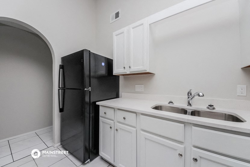 a kitchen with white cabinets and a black refrigerator