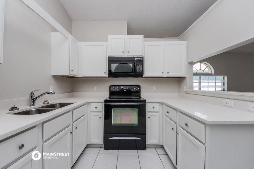 a kitchen with white cabinets and black appliances and a sink