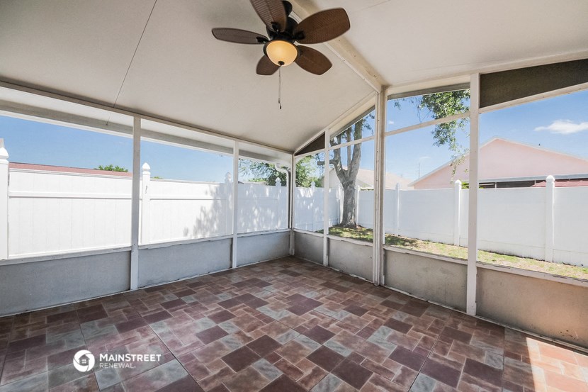 a screened in porch with large windows and a ceiling fan