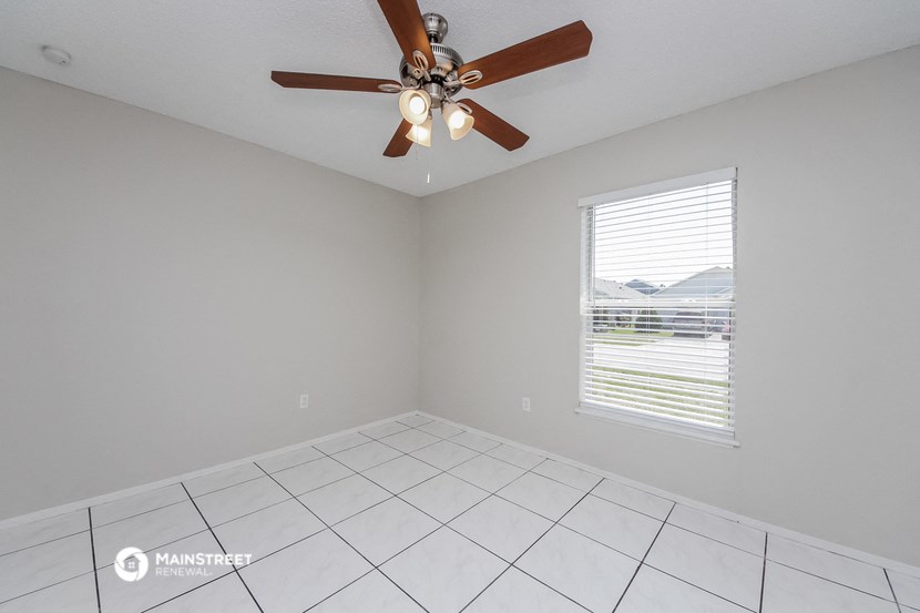 the living room has a large window and a ceiling fan