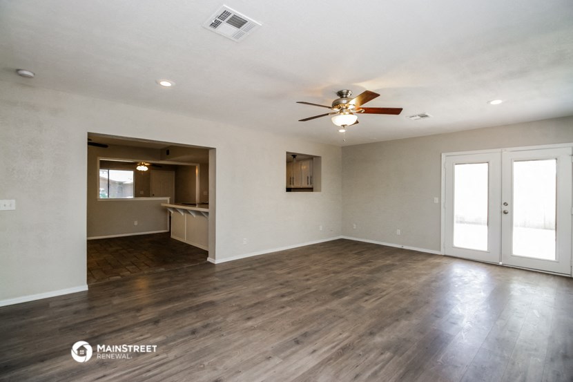 the living room of an empty house with a ceiling fan