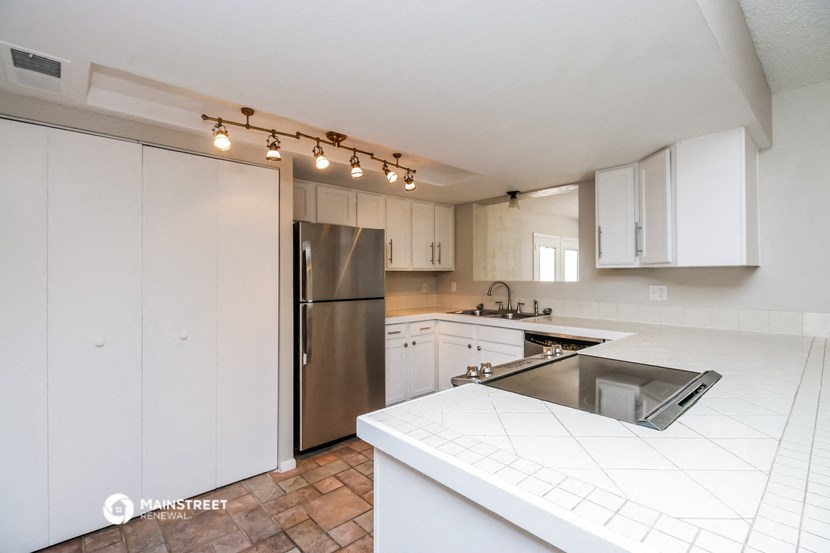 a white kitchen with stainless steel appliances and white counter tops