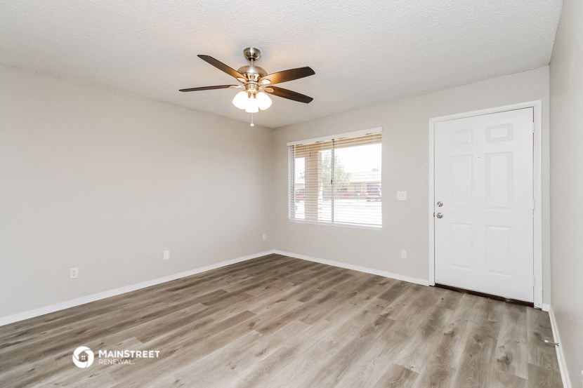 the spacious living room with wood flooring and a ceiling fan