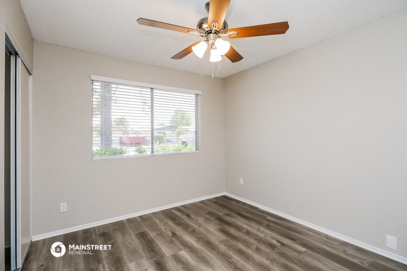 the spacious living room has a large window and a ceiling fan