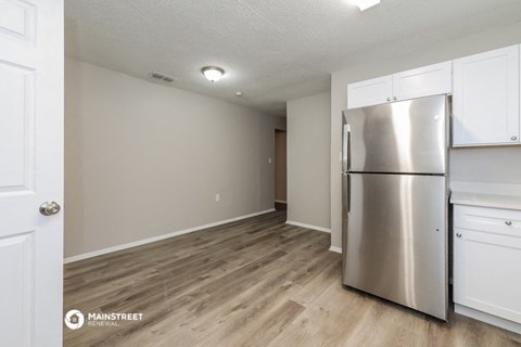 a renovated kitchen with stainless steel refrigerator and white cabinets