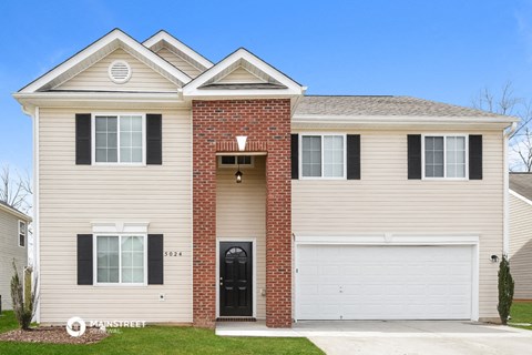 a tan house with black shutters and a white garage door
