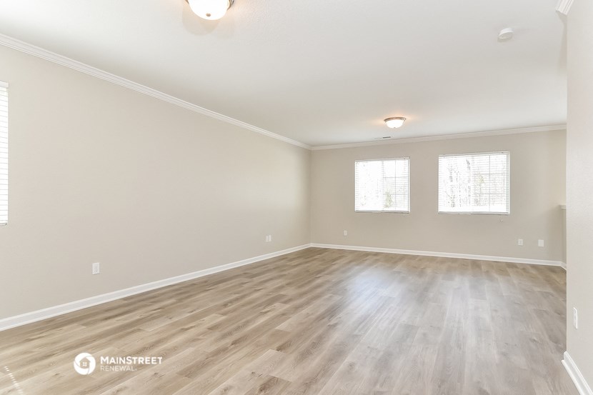 the spacious living room with hardwood flooring and two windows