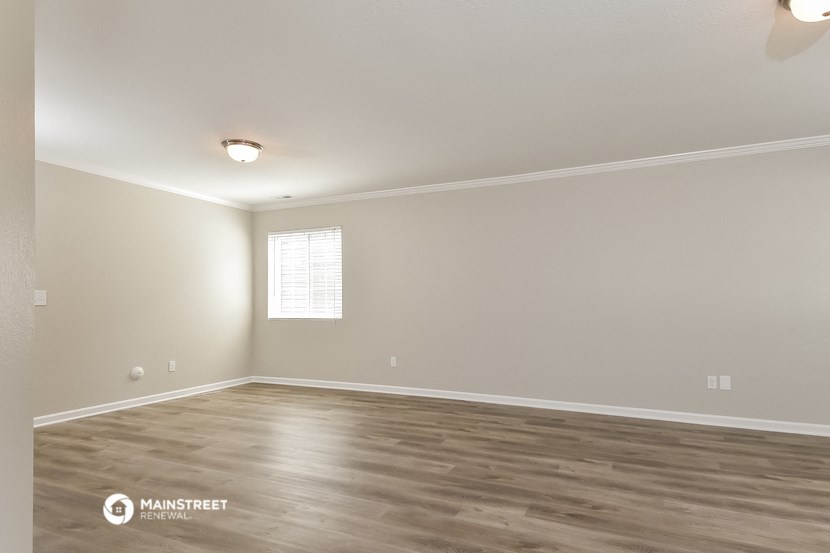 the spacious living room with hardwood floors and a window