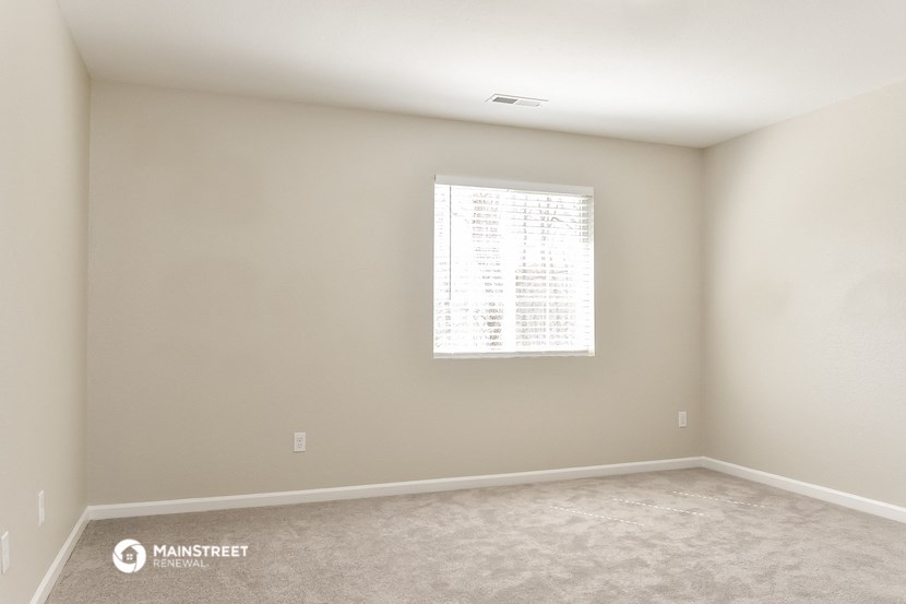 an empty room with a window and carpet