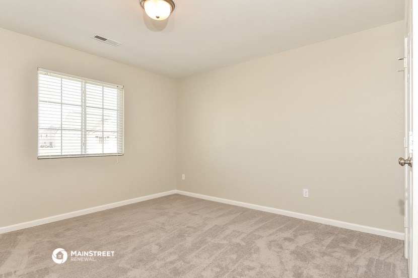 the spacious living room of a manufactured home with carpet and a window