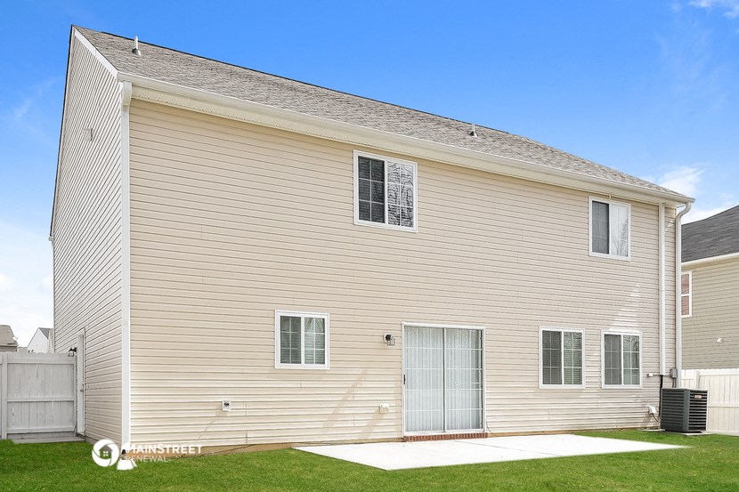 a side view of a white house with a garage and a lawn