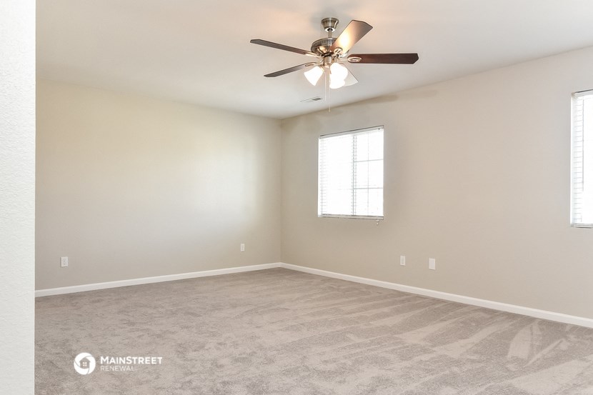 the spacious living room with carpet and ceiling fan