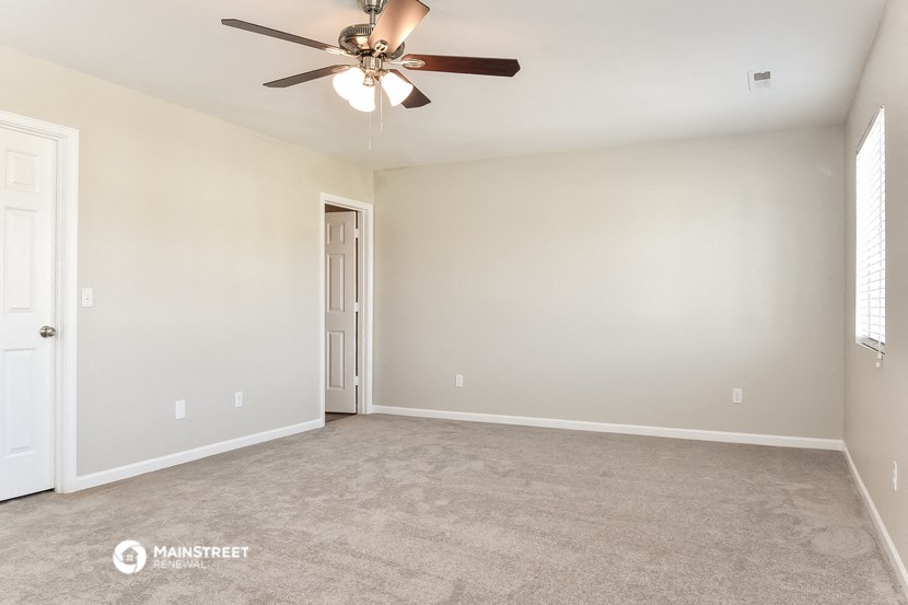 the spacious living room with ceiling fan and carpet