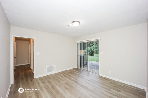 the spacious living room with wood flooring and sliding door to the yard