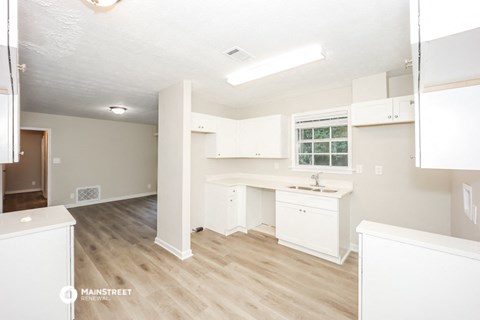 a white kitchen with a wooden floor and white cabinets