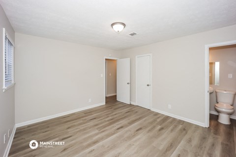 the living room of an apartment with white walls and wood flooring