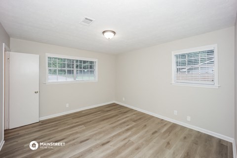 the spacious living room with hardwood flooring and two windows