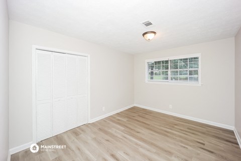 the spacious living room with wood flooring and a large window