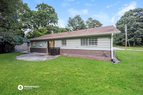 a small white house with a driveway and a grassy yard