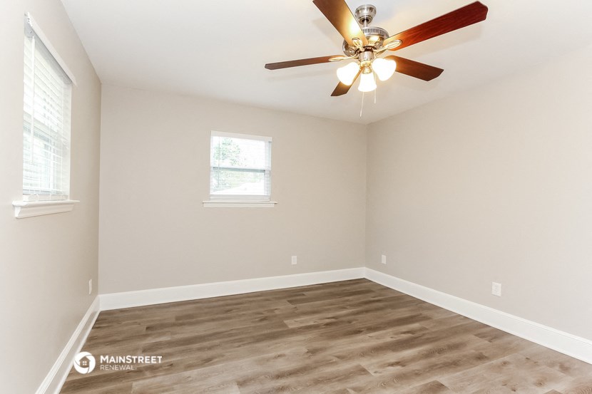 an empty bedroom with a ceiling fan and a window
