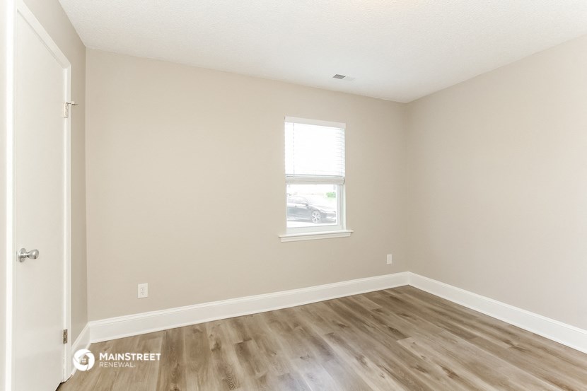 an empty room with a window and wooden floors