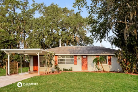 a small white house with a yard and trees
